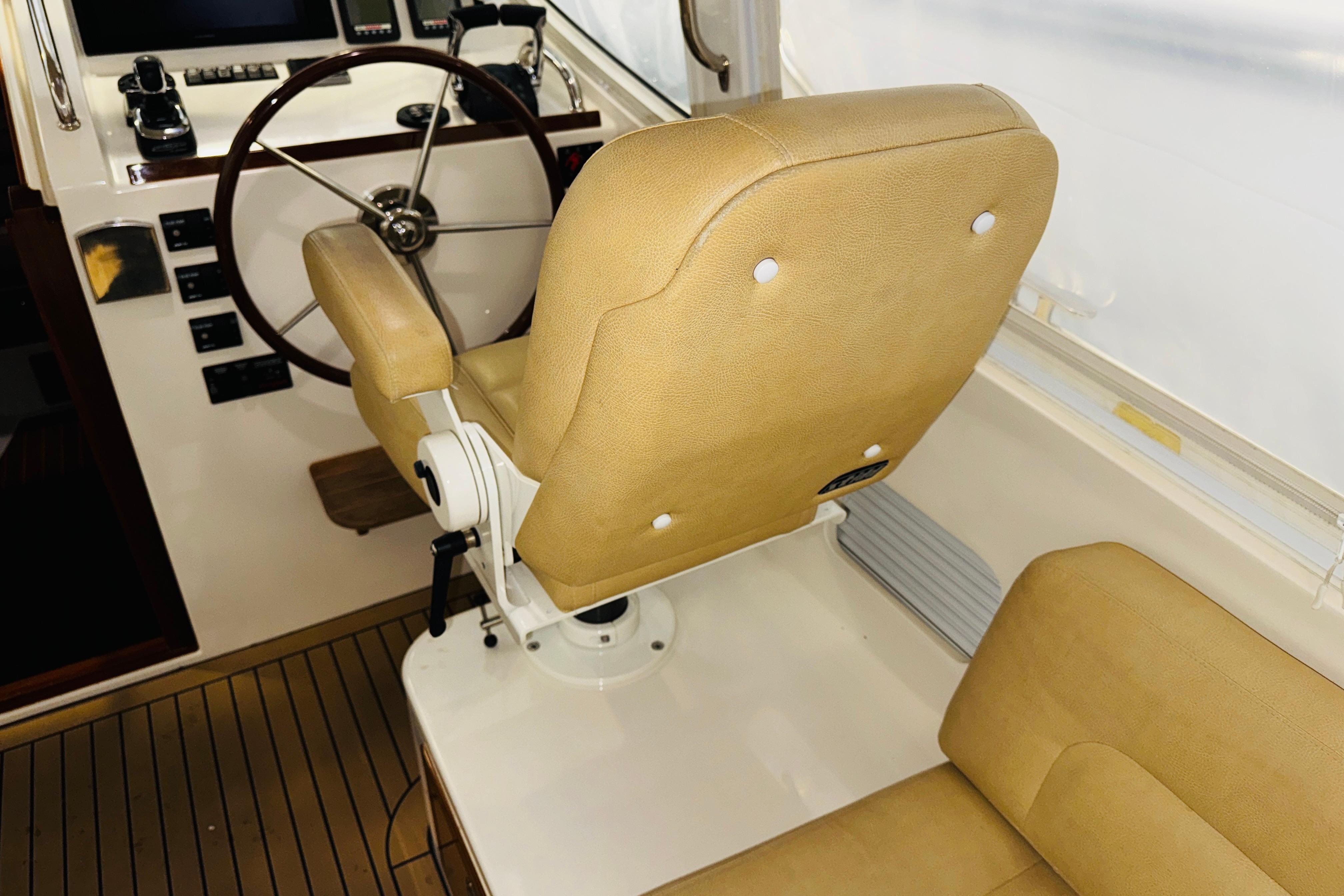 Captainu0027s chair and helm of 2015 MJM 36z Express boat, featuring tan upholstery.