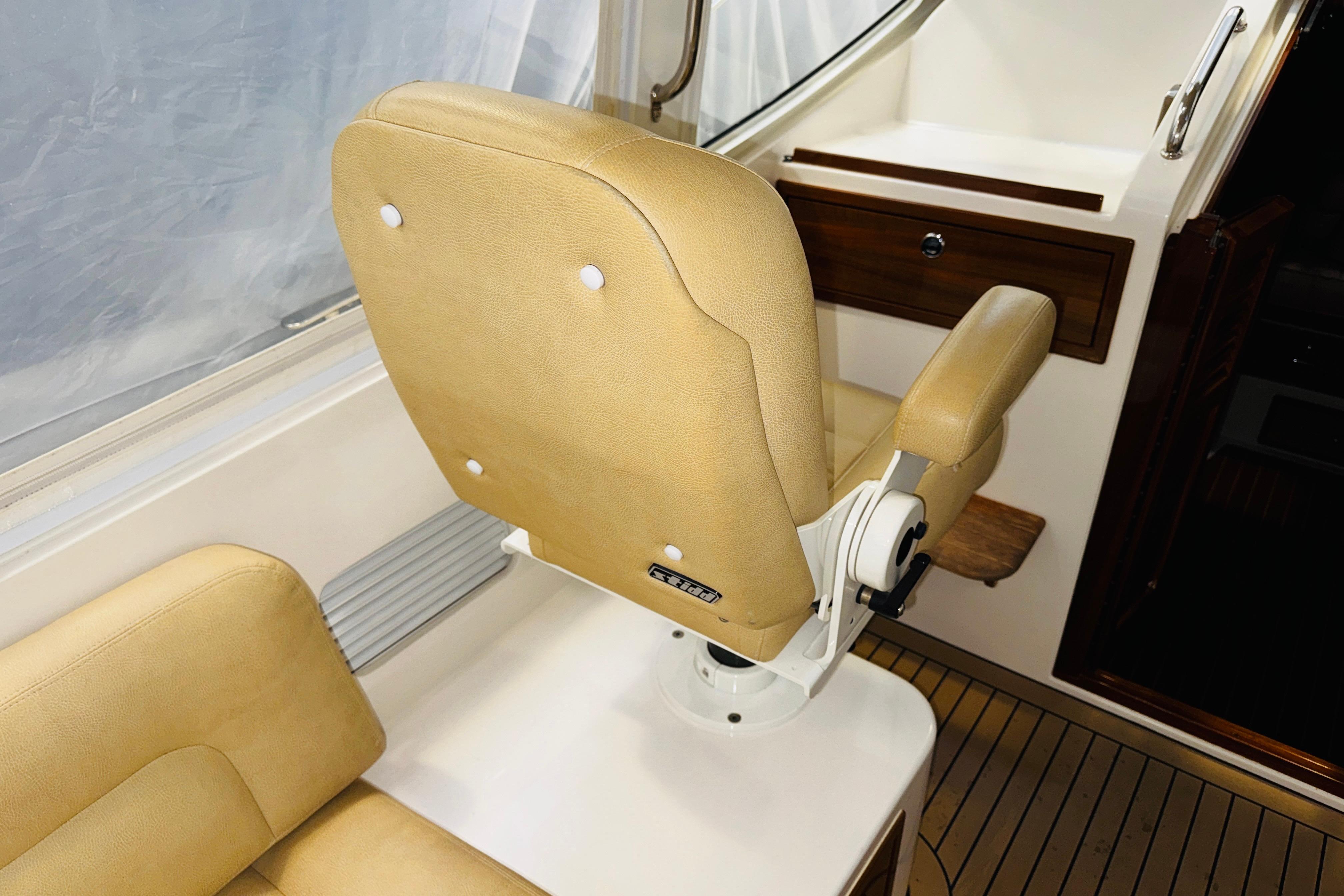 Captainu0027s chair on 2015 MJM 36z Express boat, featuring tan upholstery and wooden accents.