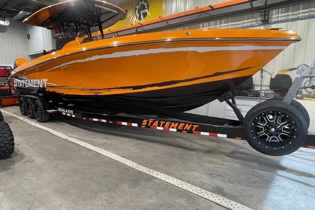 Orange 2019 Statement 350 boat on trailer in indoor storage facility.