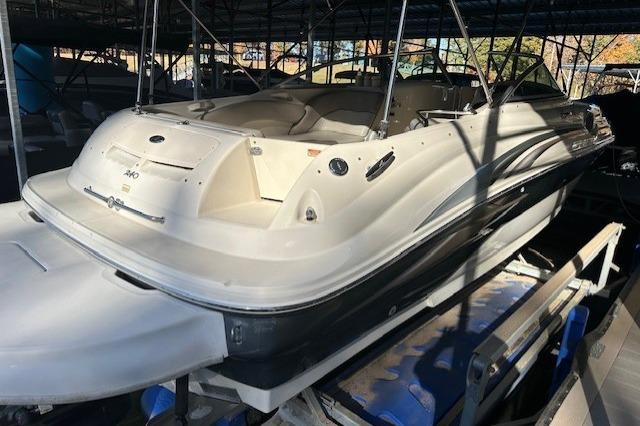 2002 Sea Ray 240 Sundeck boat in a covered marina, showcasing sleek design and spacious seating.