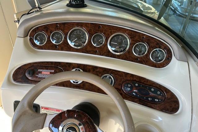 Dashboard of 2002 Sea Ray 240 Sundeck boat with gauges and steering wheel.