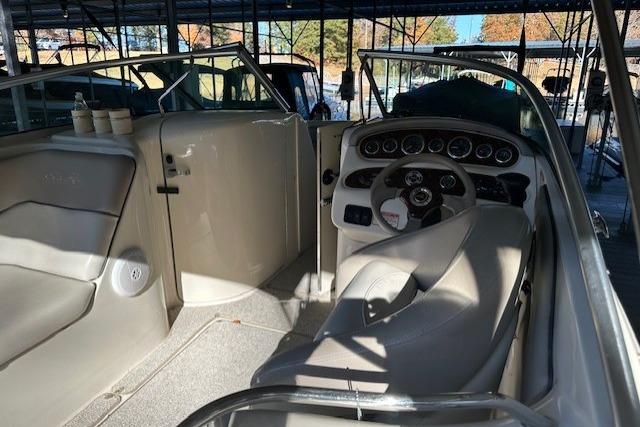 2002 Sea Ray 240 Sundeck interior with steering wheel and seating under covered dock.