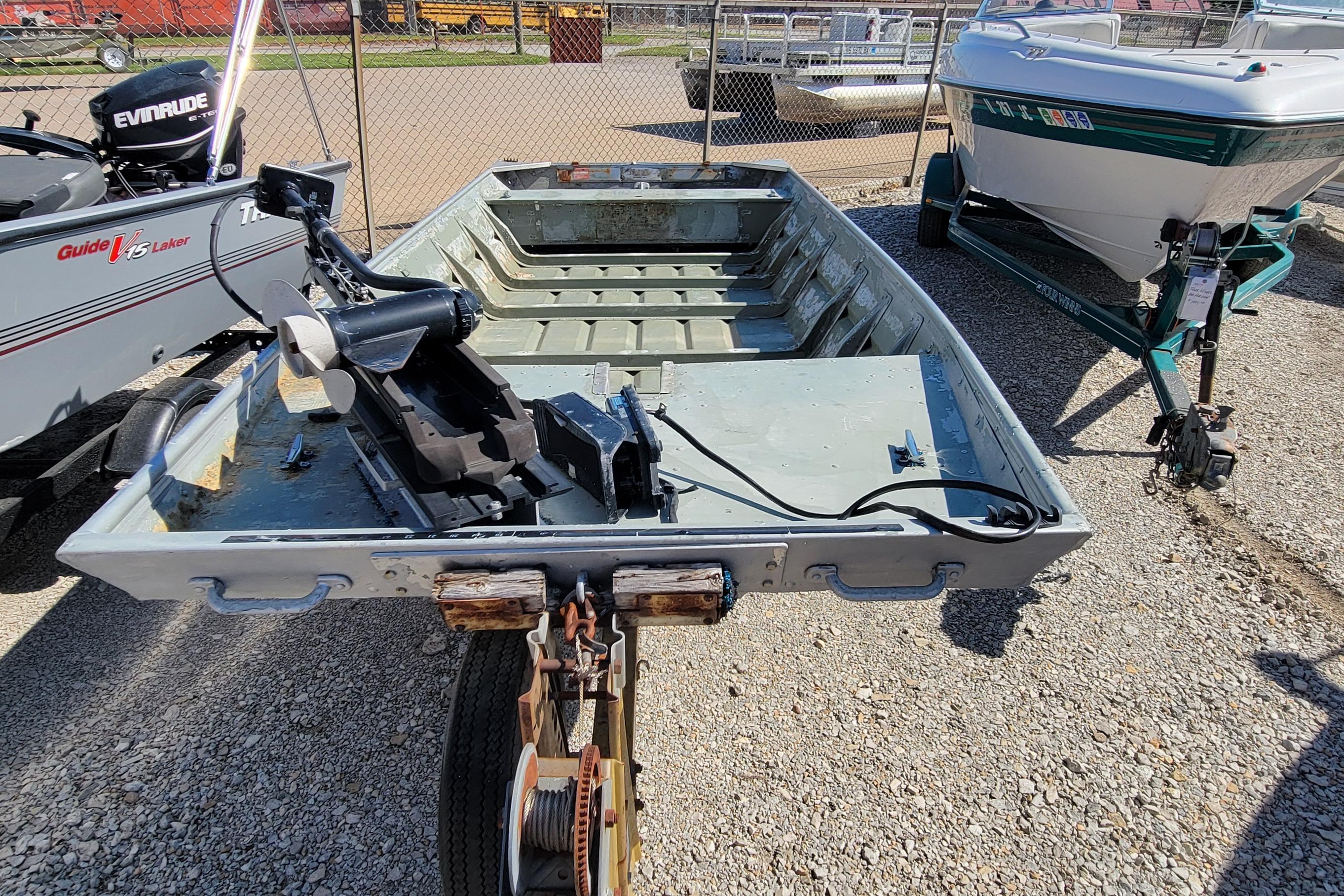 1973 Monark 14 Jon boat on trailer, parked outdoors with motor attached.