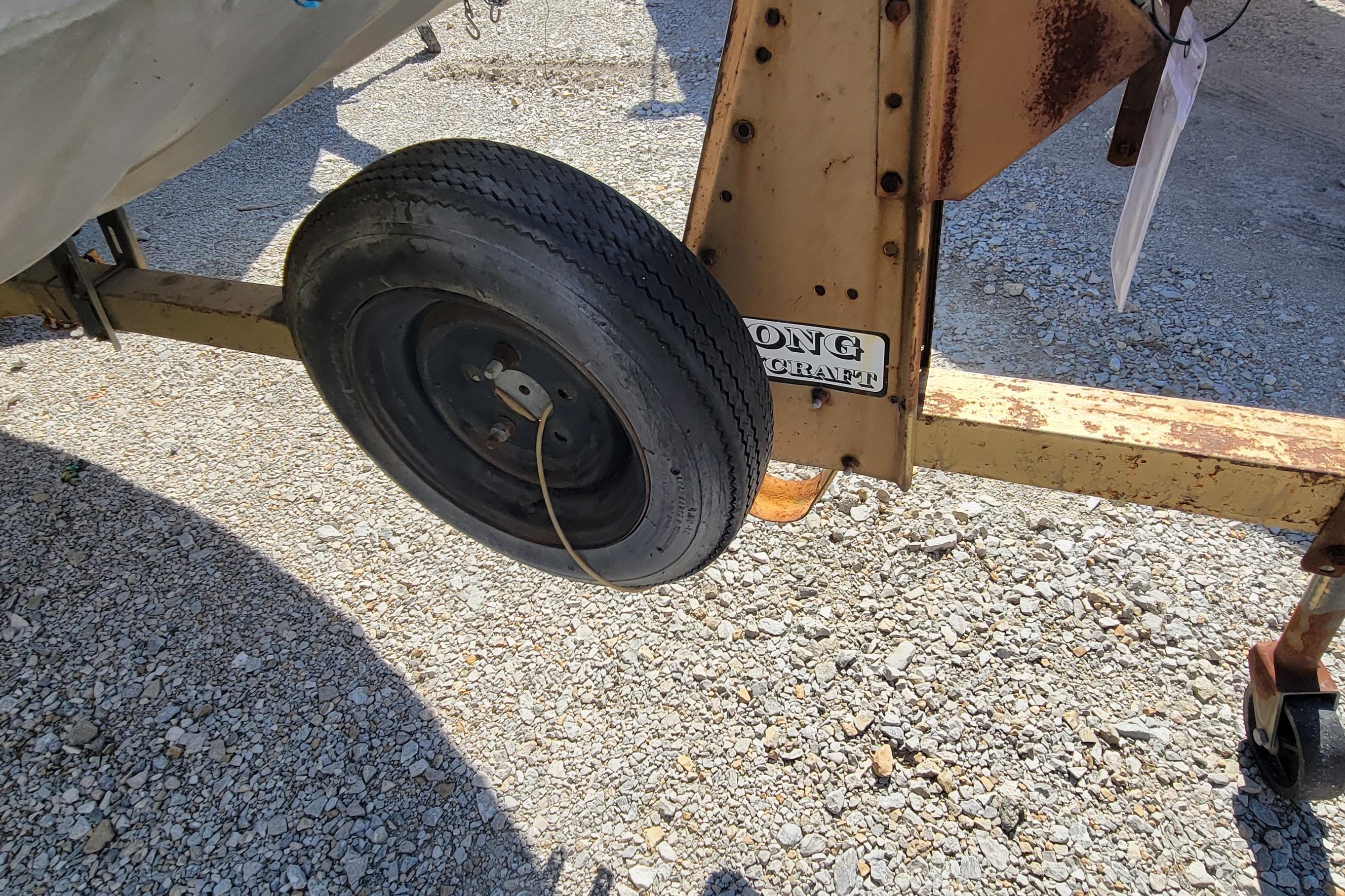1973 Monark 14 Jon boat trailer wheel on gravel surface.