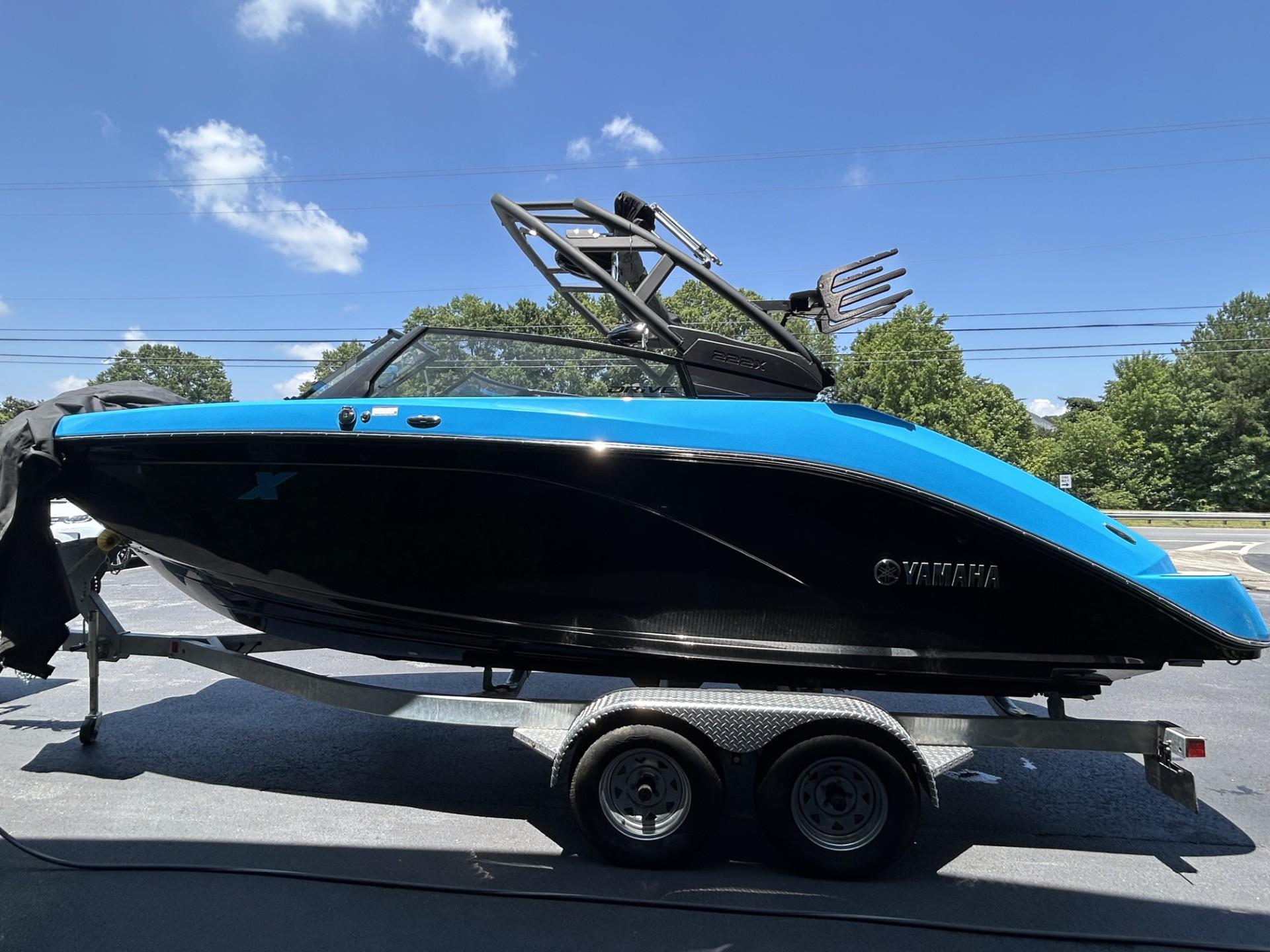 2023 Yamaha Boats 222 XD in blue and black on a trailer under a clear sky.