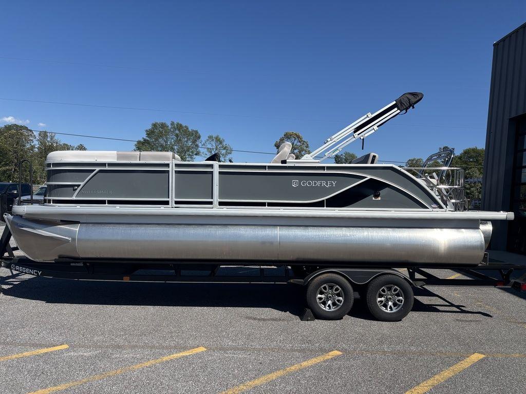 2025 Godfrey Sweetwater 2286 SFLC pontoon boat on a trailer, parked outdoors.