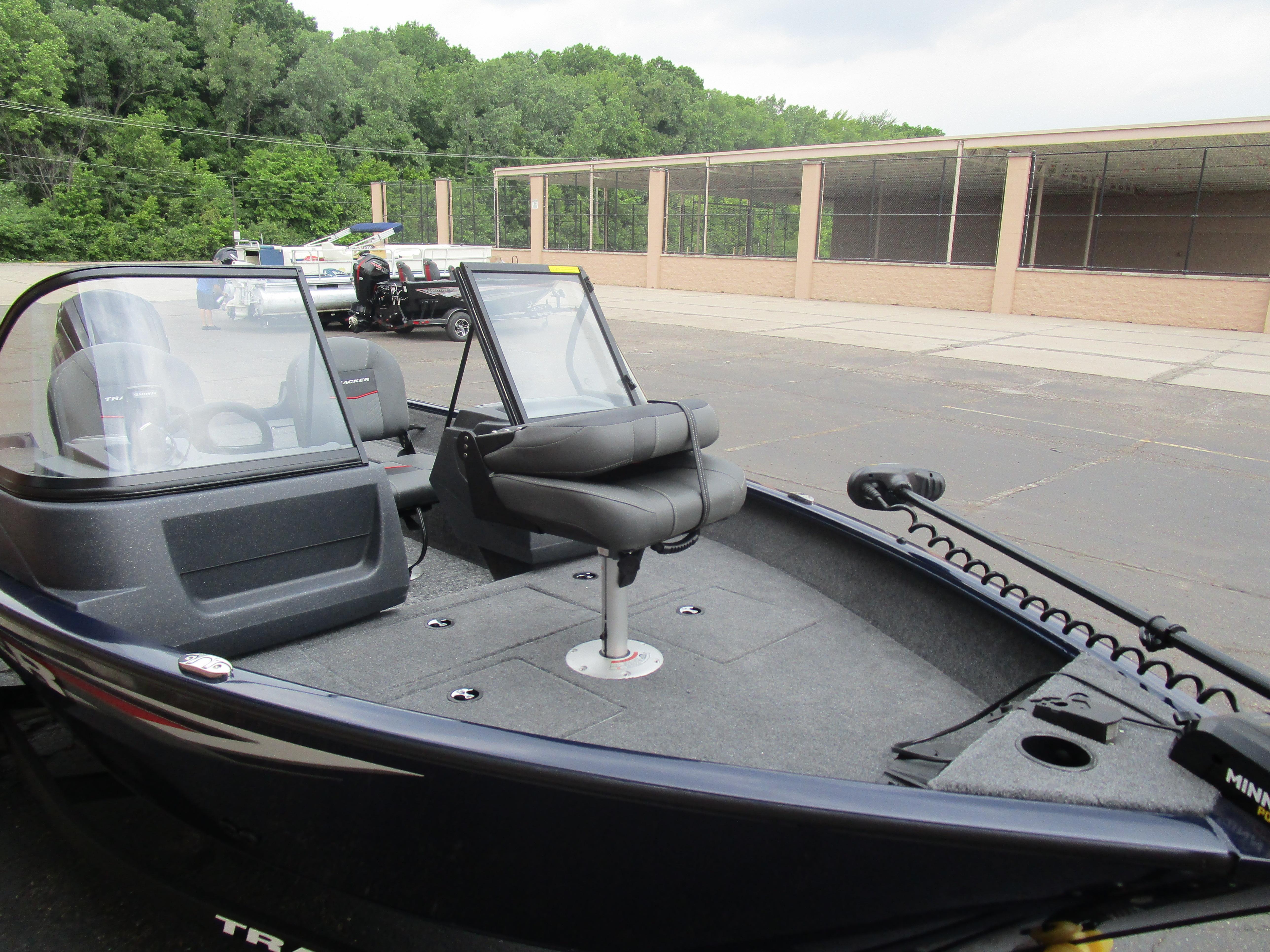 2025 Tracker Pro Guide V16 WT boat with seating, windshield, and trolling motor in a parking lot.