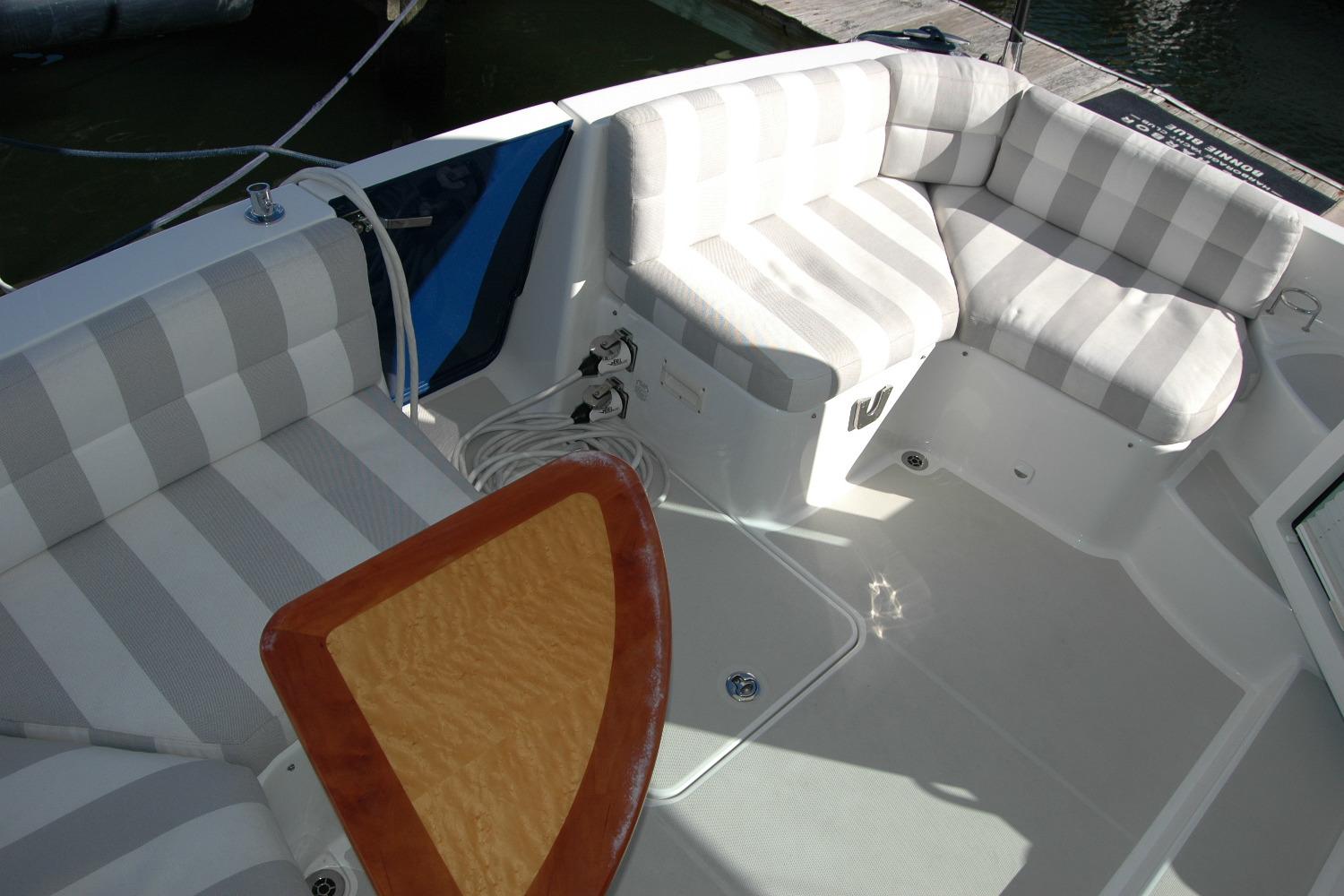 2015 Back Cove 37 boat with striped seating and wooden table in cockpit area.