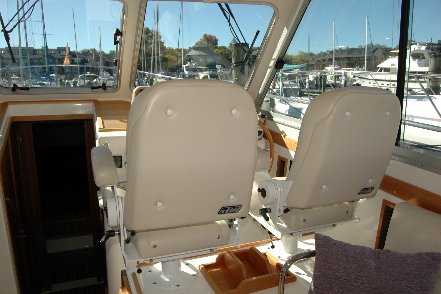 Interior of 2015 Back Cove 37 boat with helm seats and marina view.