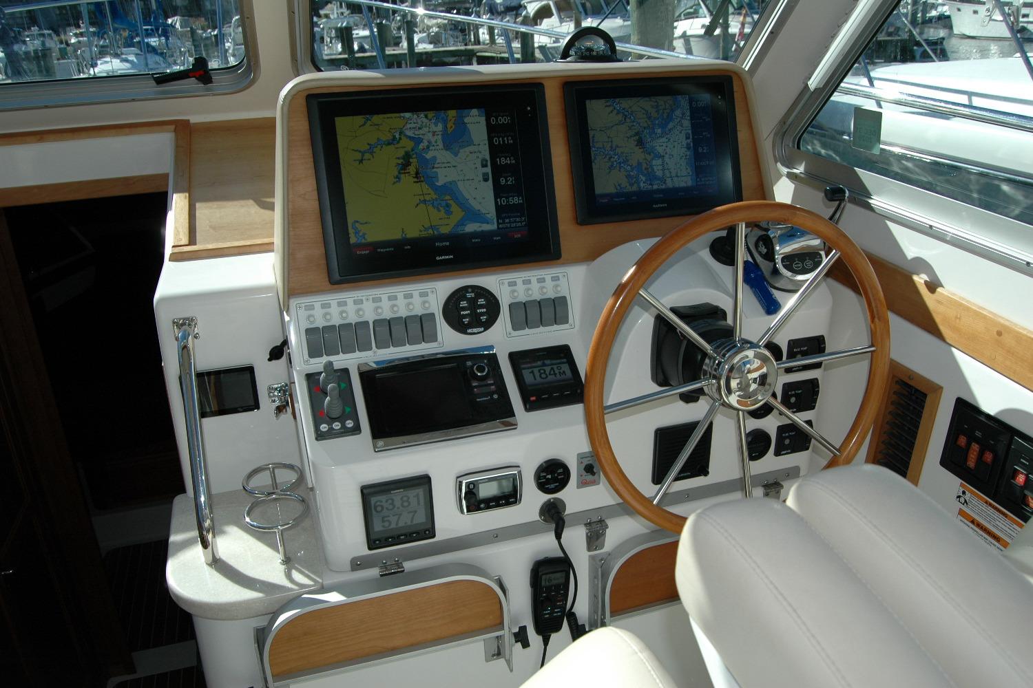 2015 Back Cove 37 helm with dual navigation screens and wooden steering wheel.