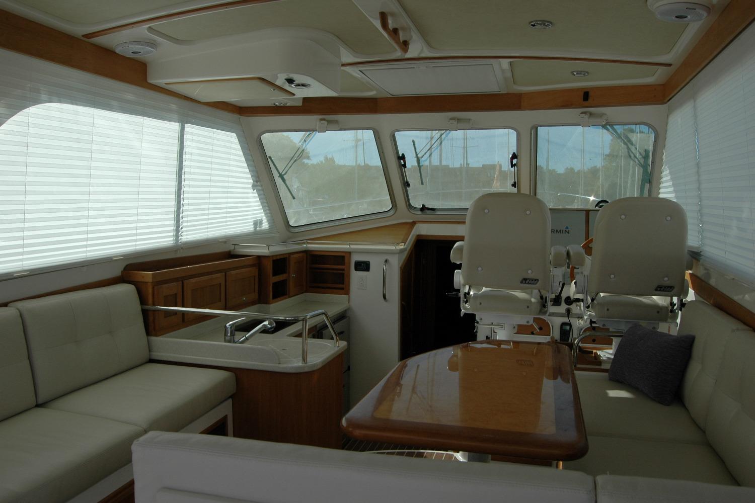 Interior of 2015 Back Cove 37 yacht with seating, helm chairs, and windows.