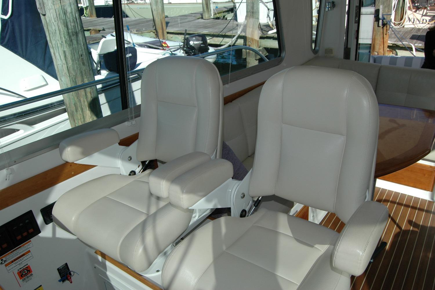 2015 Back Cove 37 interior with two white captain chairs and wooden accents.
