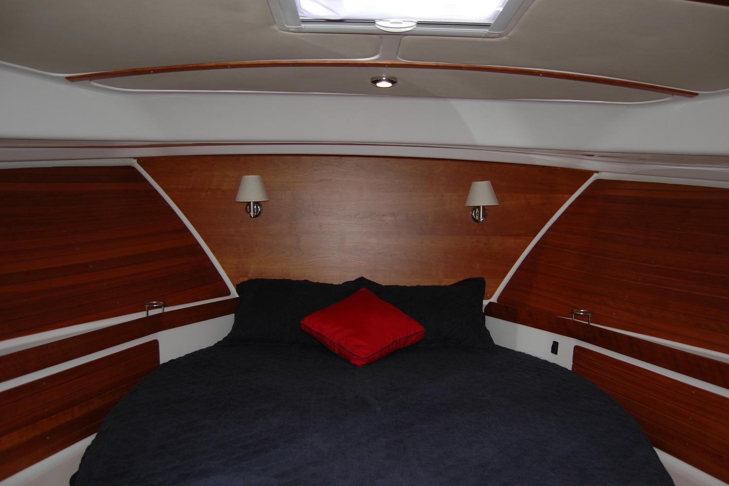 Luxurious cabin interior of 2015 Back Cove 37 yacht with wood paneling and cozy bedding.