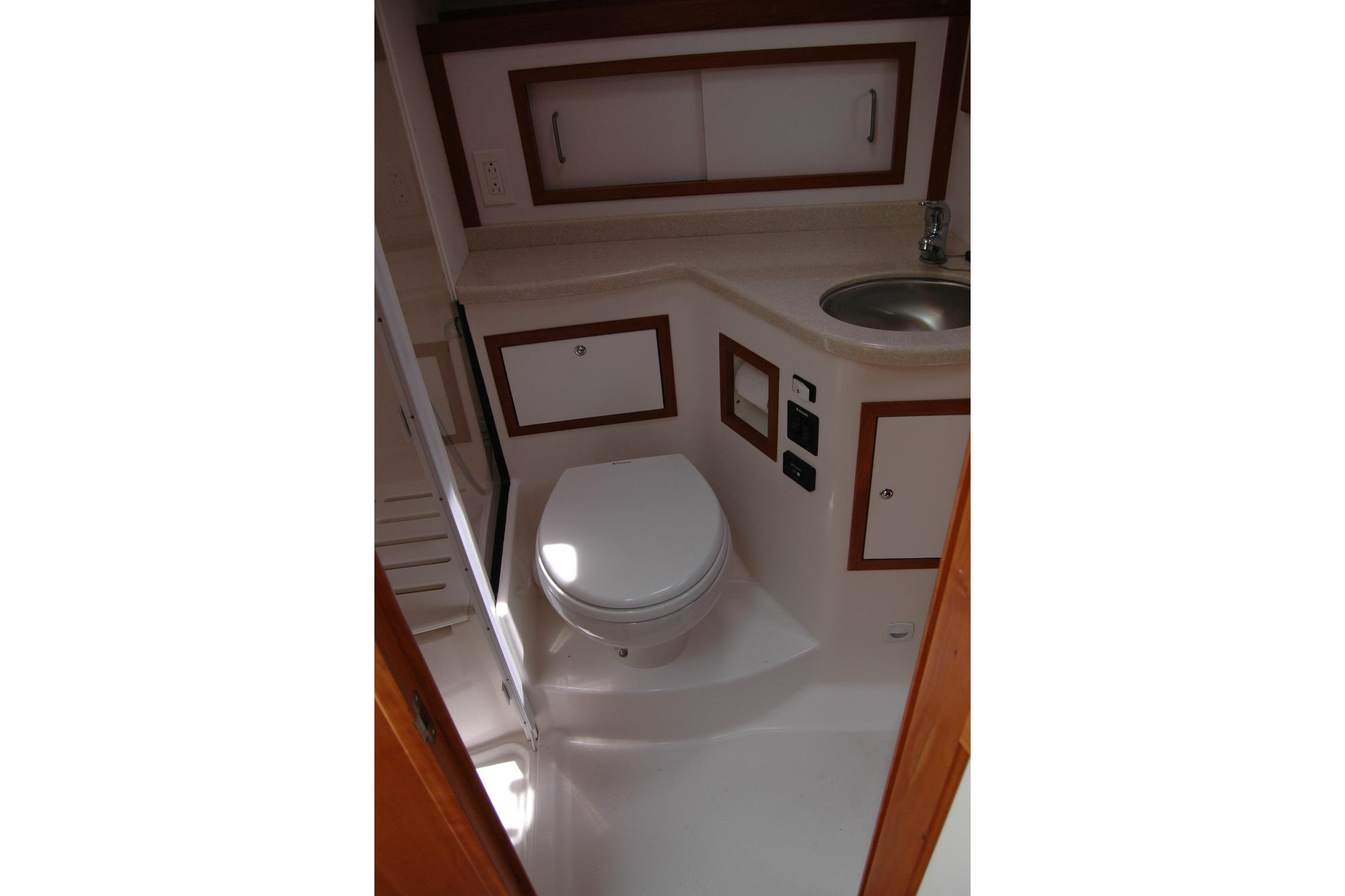 2015 Back Cove 37 yacht bathroom with toilet, sink, and storage cabinets.