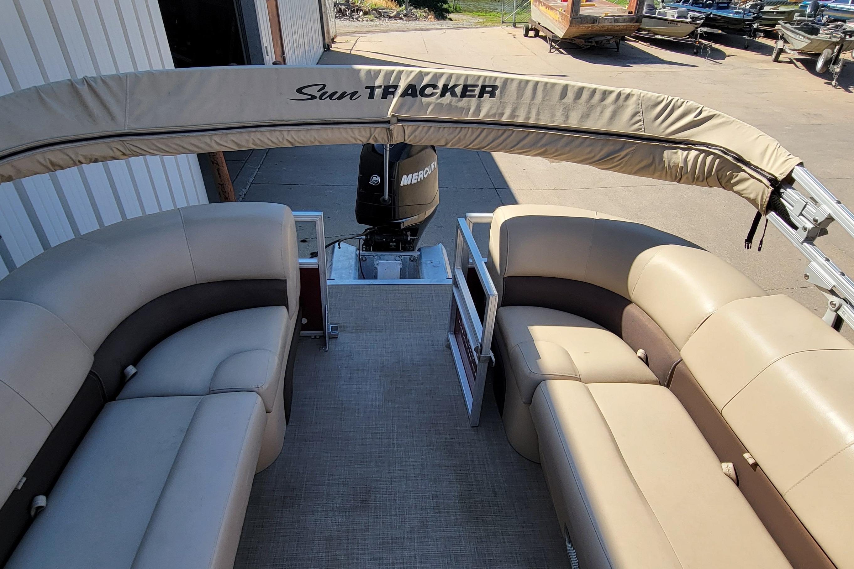 2019 Sun Tracker Party Barge 24 DLX with beige seating and canopy, docked outdoors.