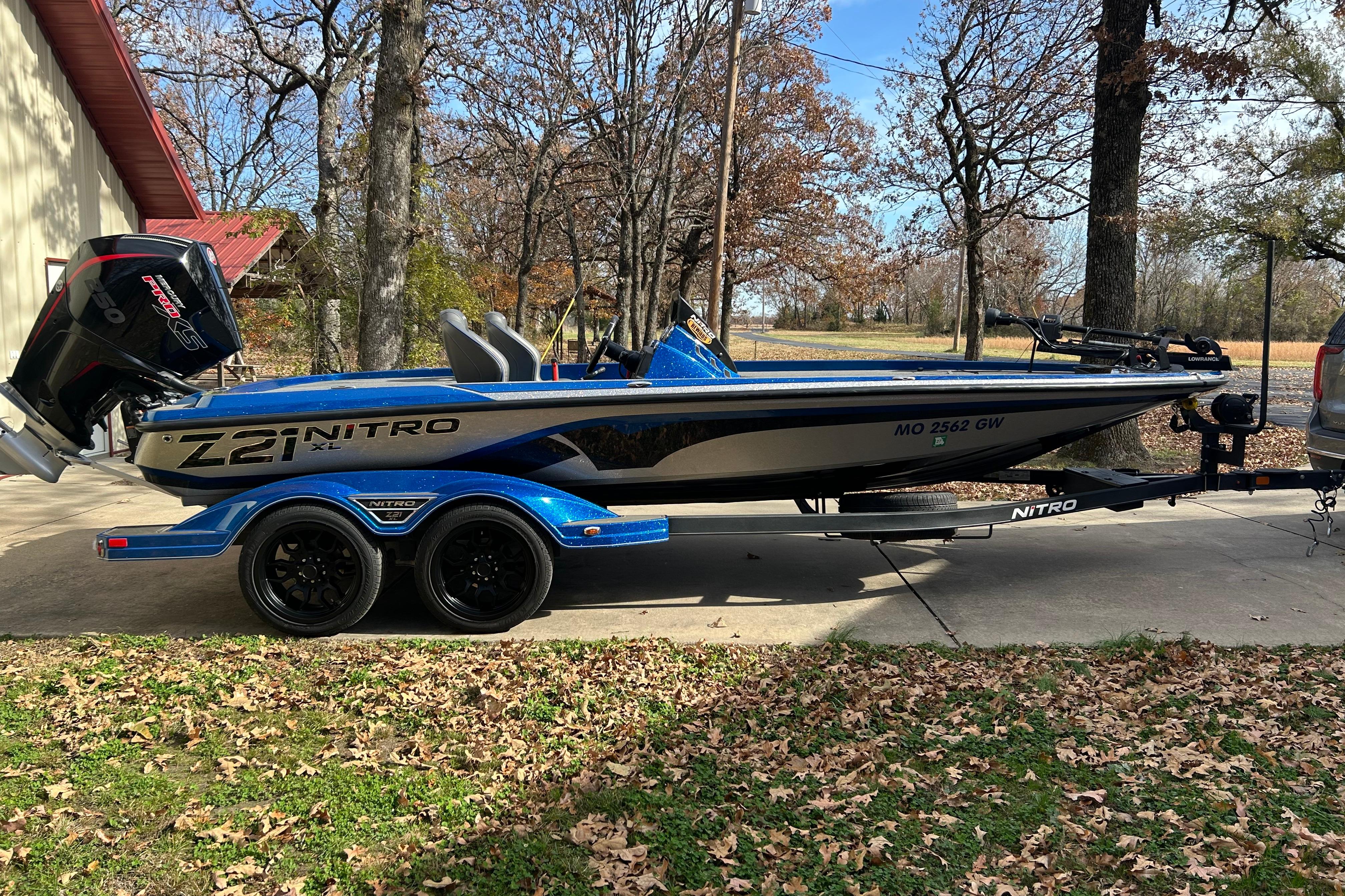 2024 Nitro Z21 XL Pro boat on trailer, parked outdoors in a wooded area.
