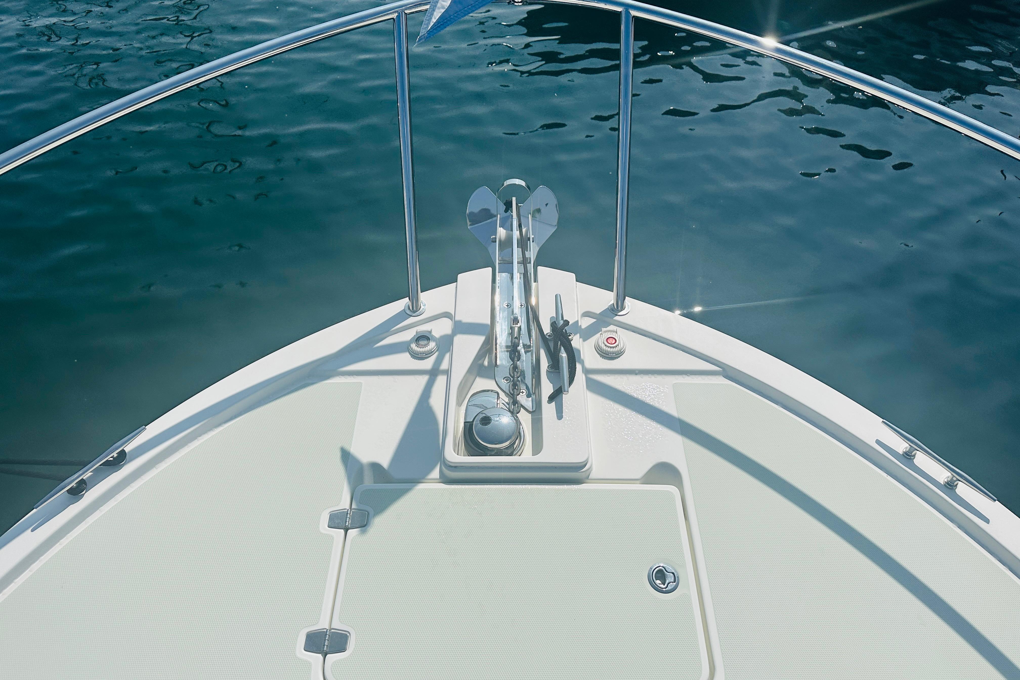 Bow of 2017 Back Cove 32 boat with anchor, railing, and calm water.