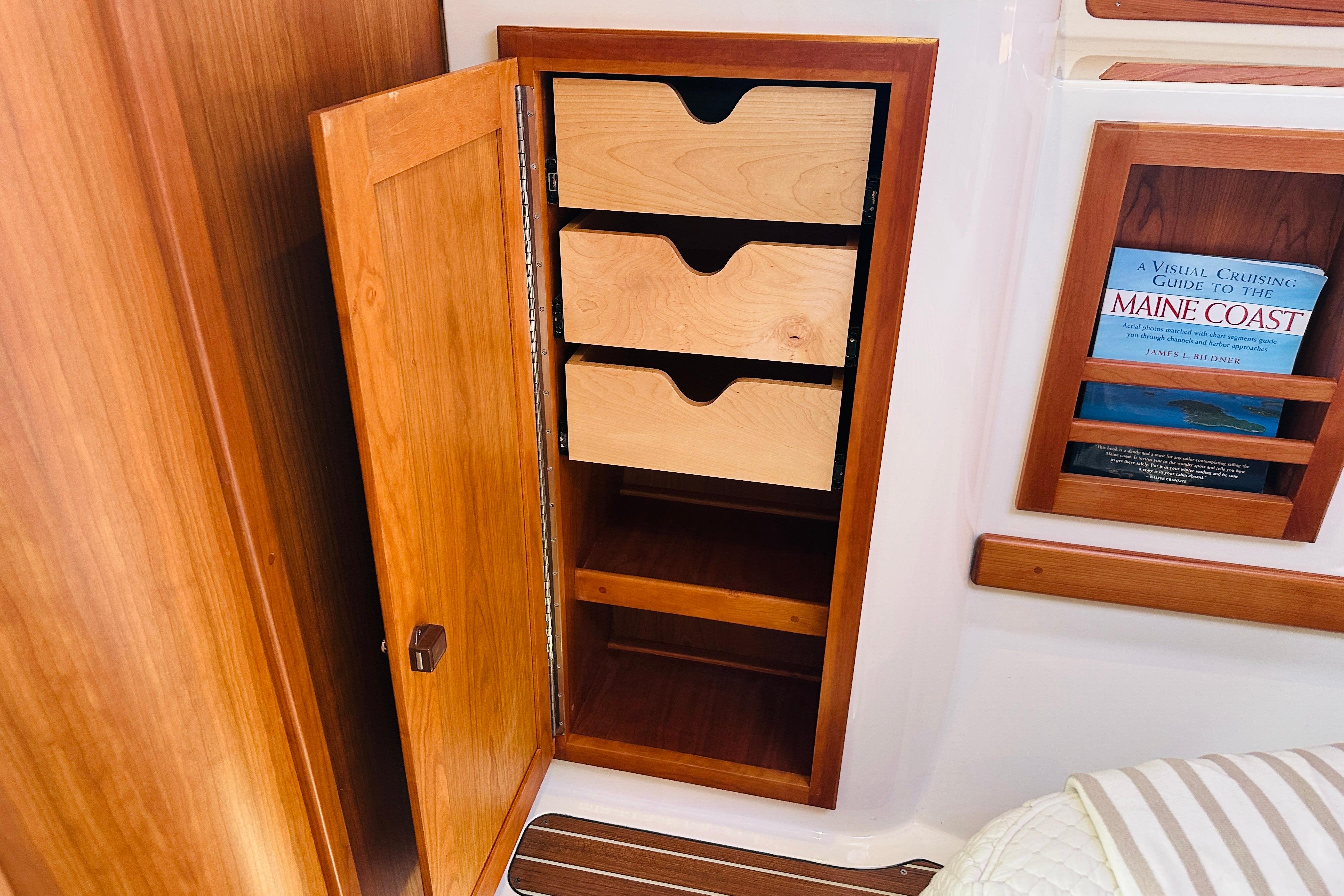Wooden cabinet with open drawers and a book on a Back Cove 32, 2017 model.