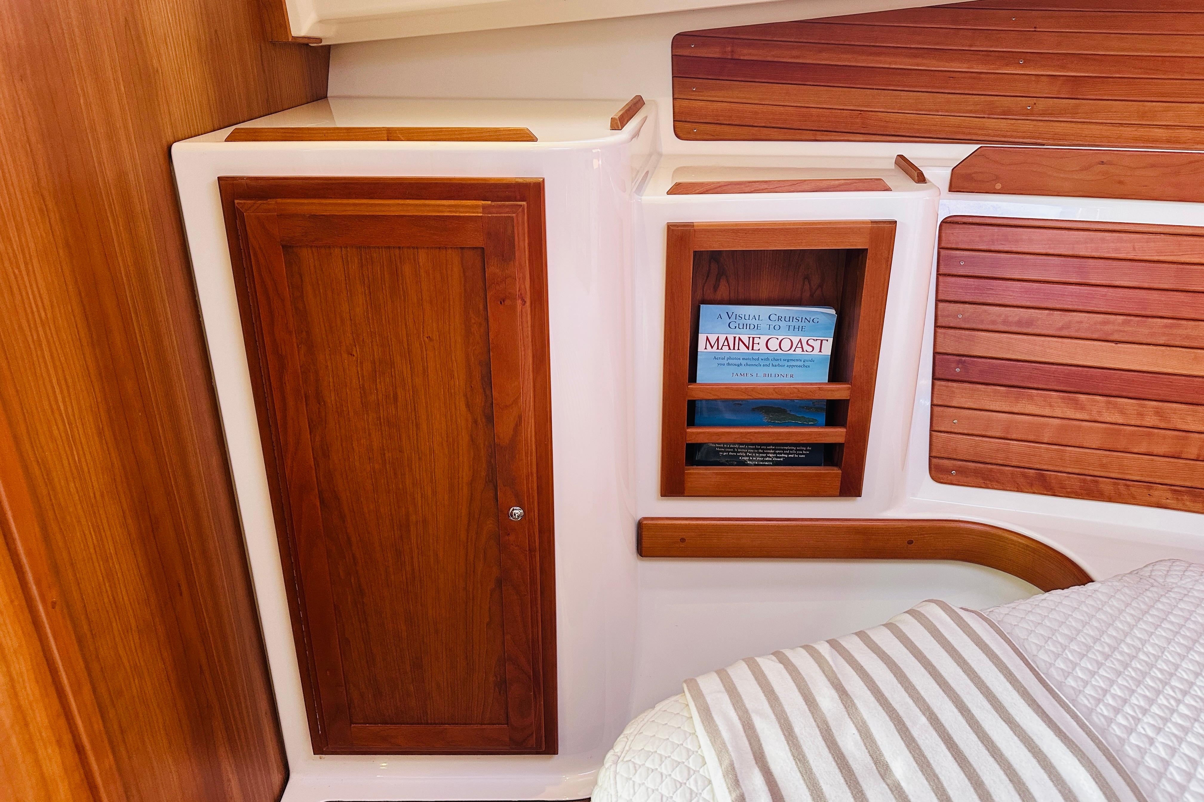 2017 Back Cove 32 cabin interior with wooden cabinetry and a book on Maine Coast cruising.