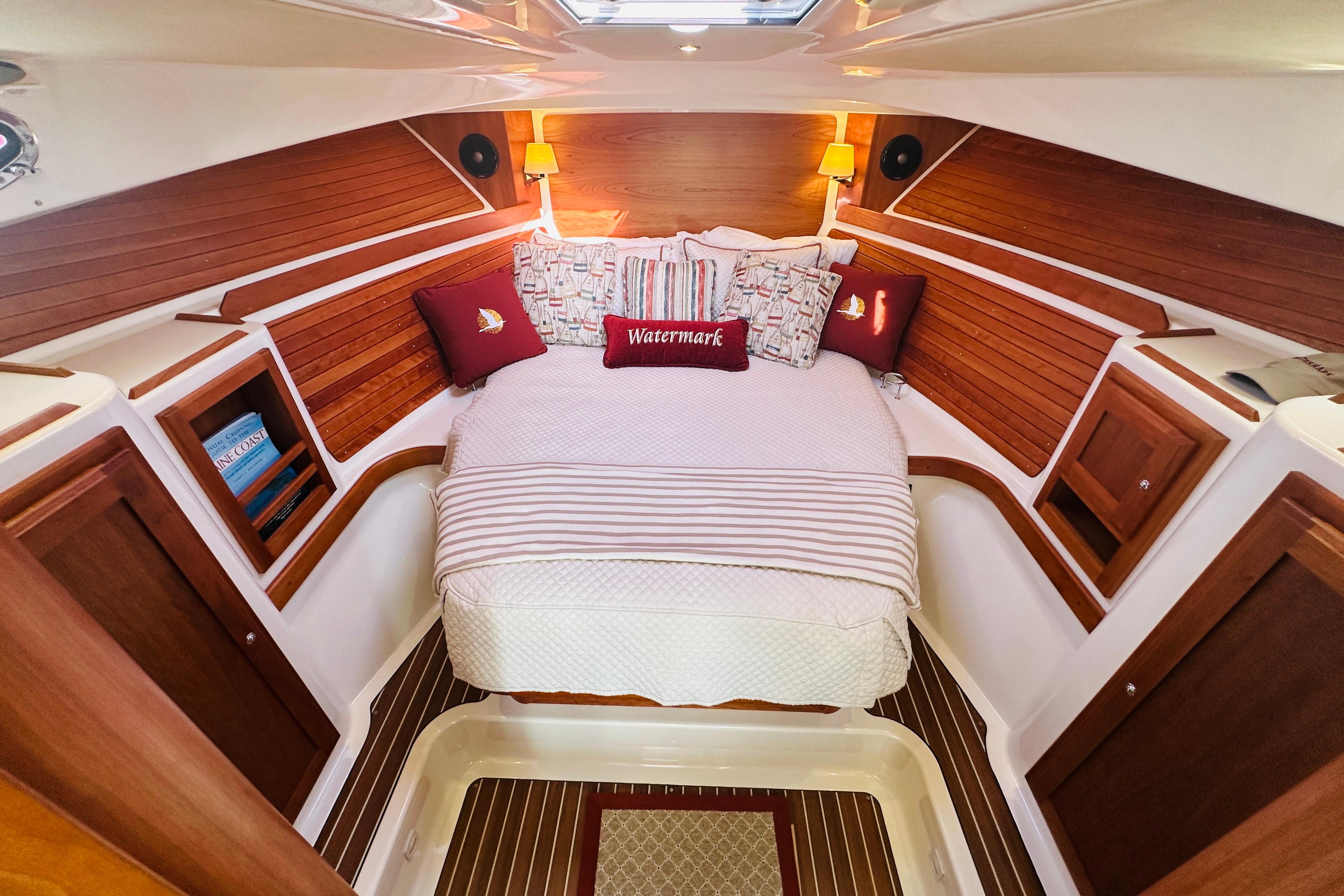 Cozy cabin interior of 2017 Back Cove 32 boat with wood paneling and plush bedding.
