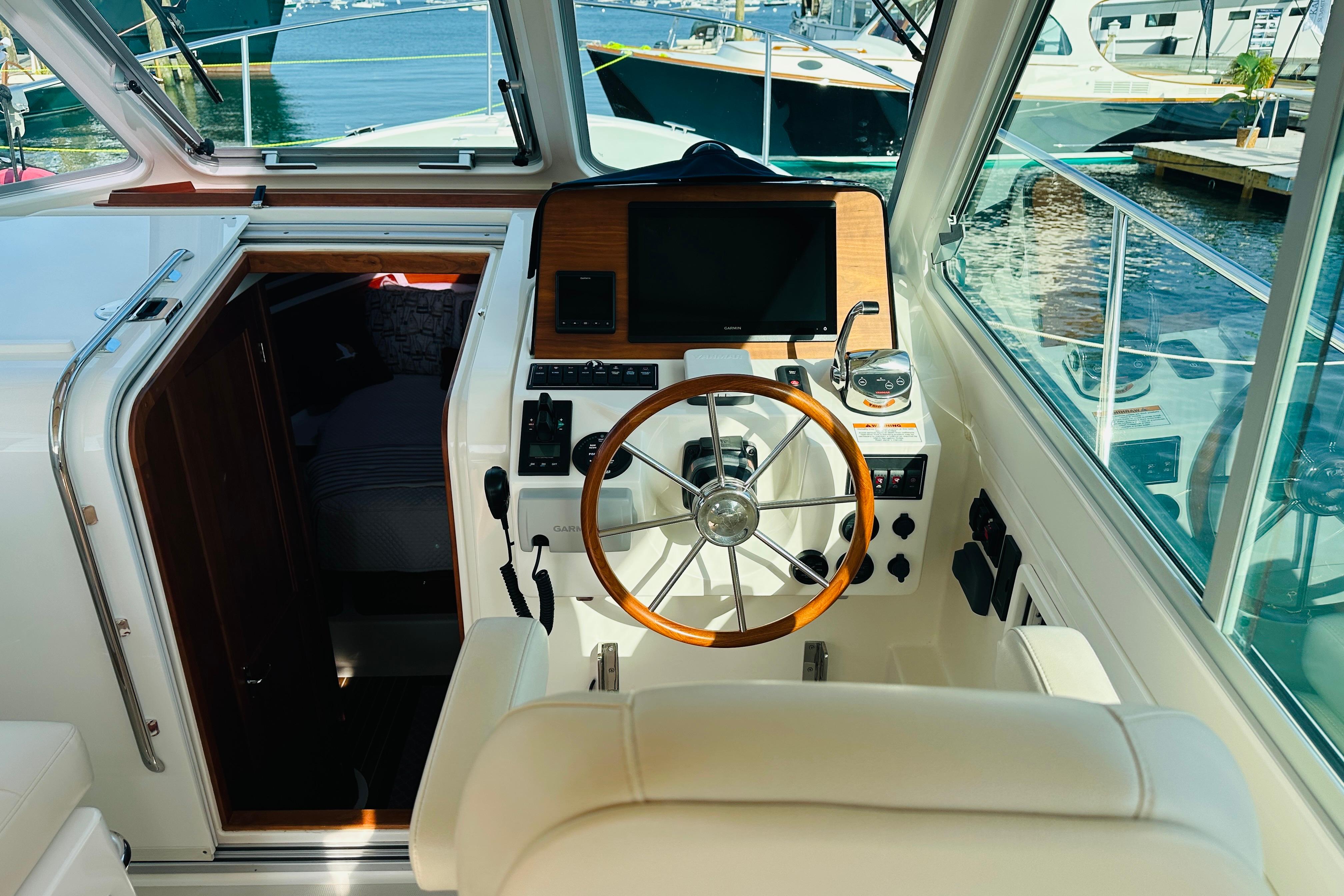 Helm of 2017 Back Cove 32 boat with wooden steering wheel and navigation equipment.