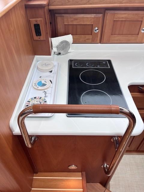 2021 Sabre 45 Salon Express kitchen with electric stove and wooden cabinetry.