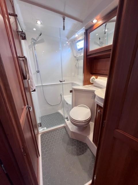2021 Sabre 45 Salon Express bathroom with shower, toilet, and wooden cabinetry.