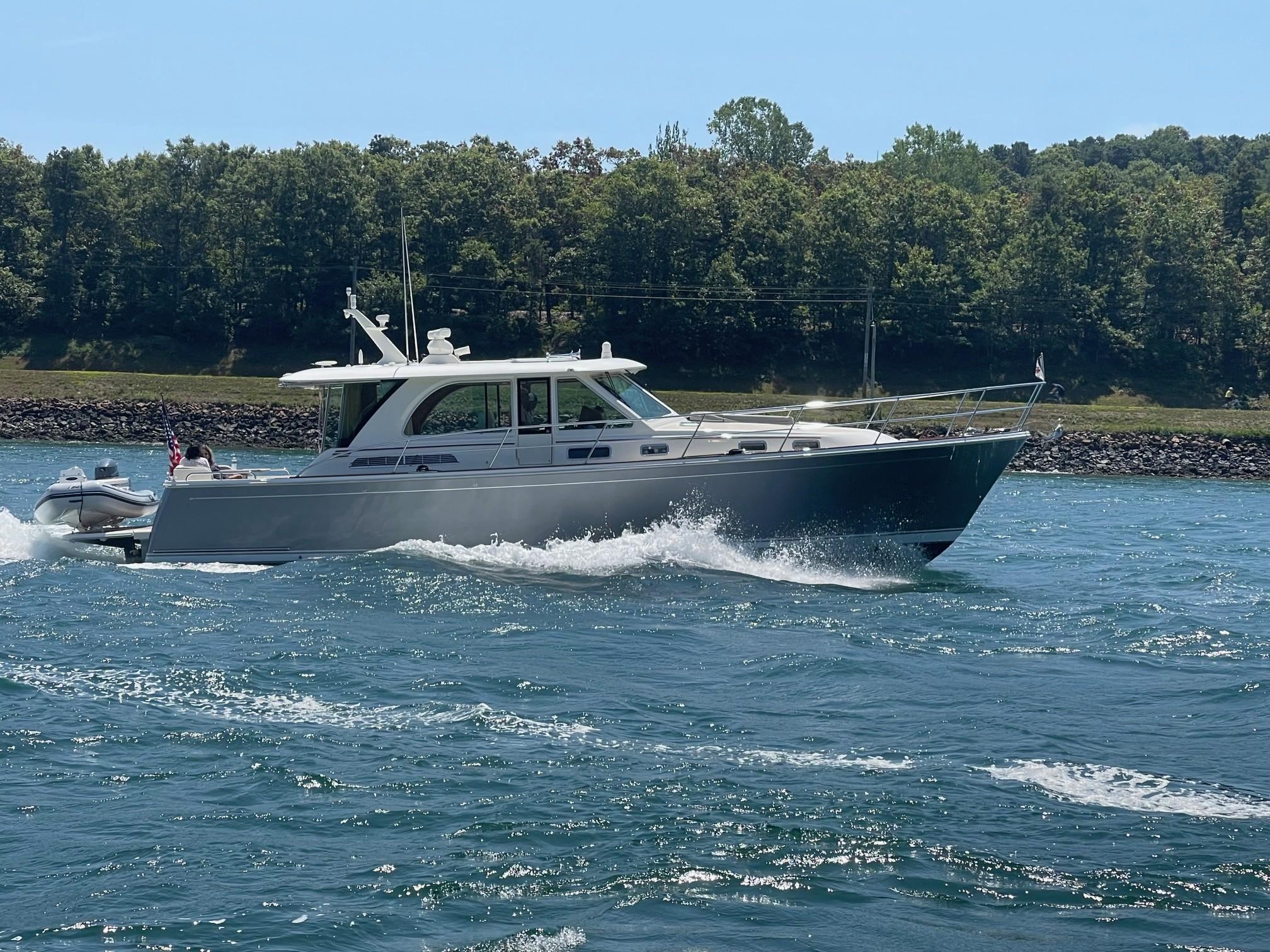 2021 Sabre 45 Salon Express cruising on a sunny day, surrounded by lush greenery.