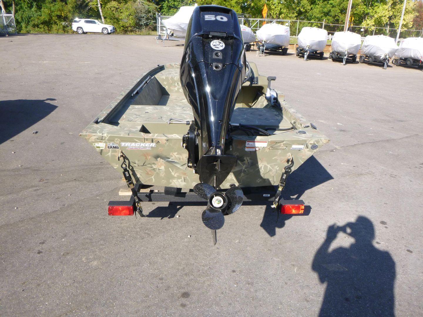 2024 Tracker Grizzly 1648 SC boat with outboard motor in parking lot.