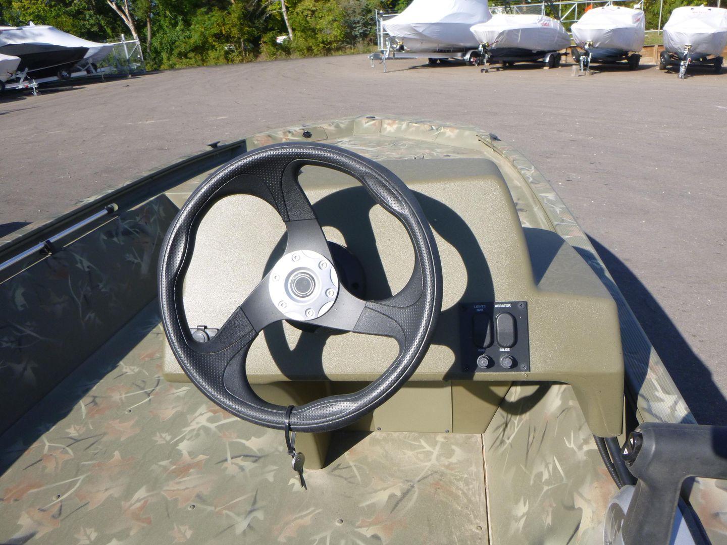 2024 Tracker Grizzly 1648 SC boat steering wheel and console in outdoor setting.