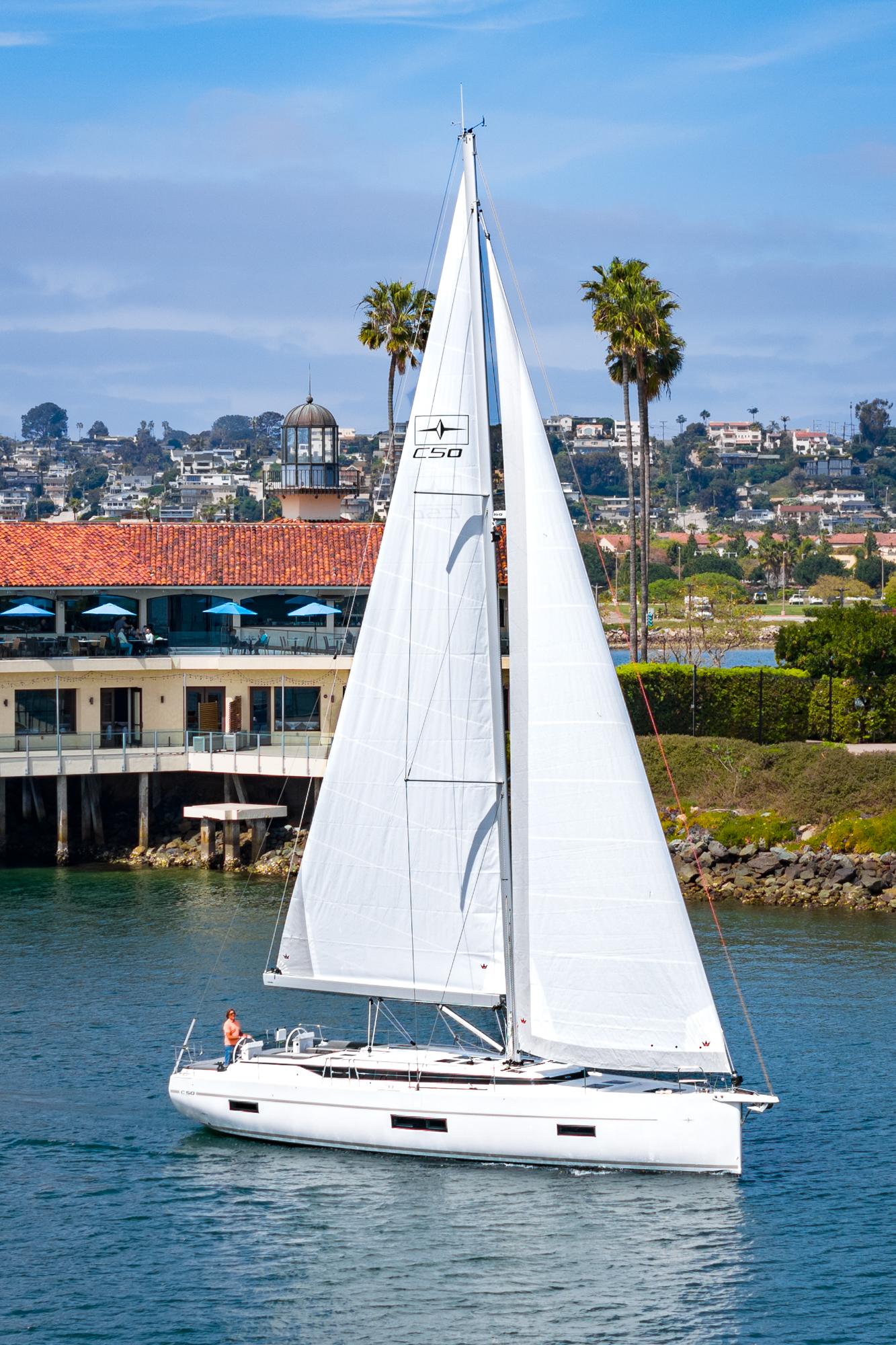 Bavaria-C50 2024-This could be yours CA-US-2024 Bavaria C50 sailboat cruising near coastal buildings and palm trees.-9654457 | Thumbnail