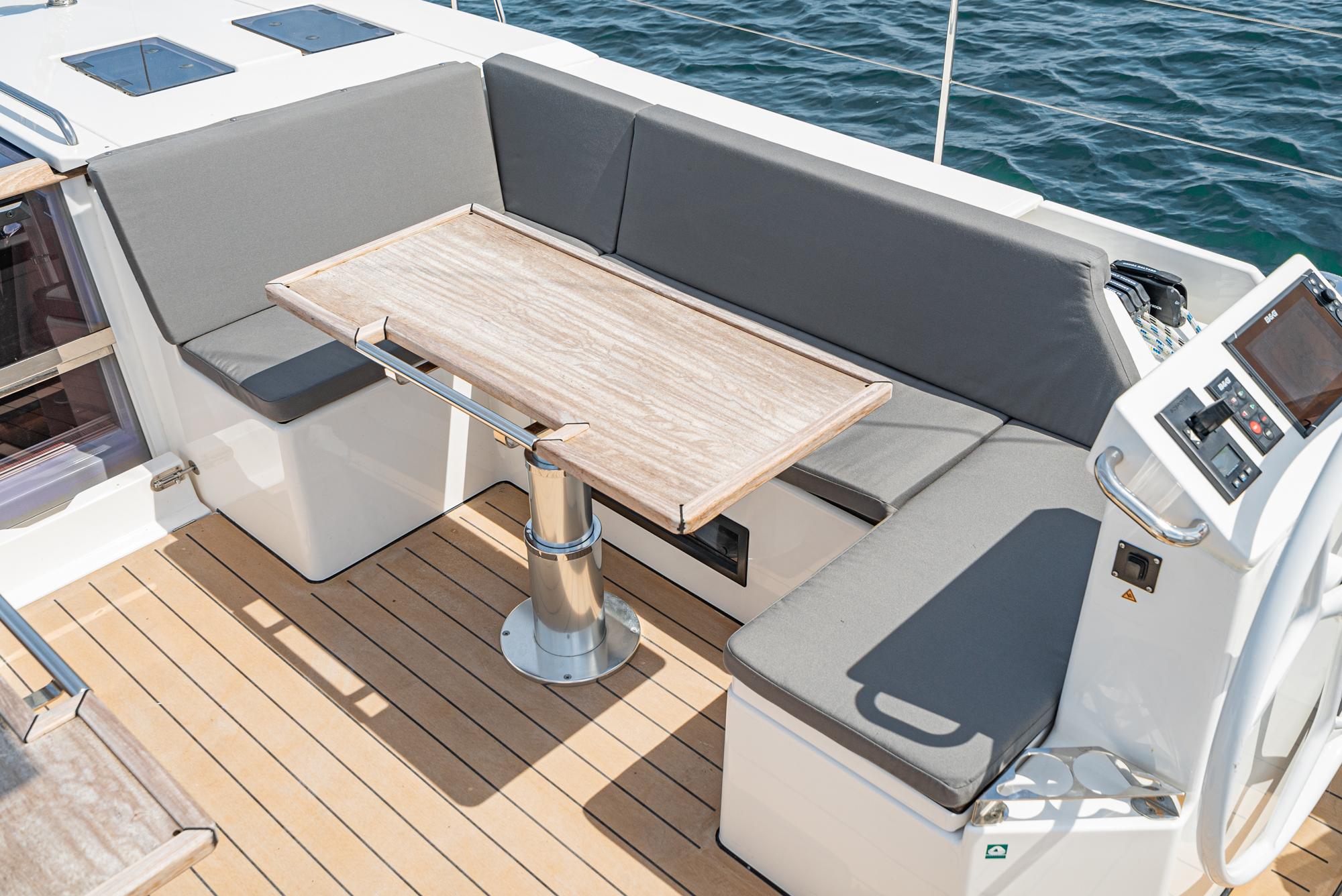 Bavaria-C50 2024-This could be yours CA-US-2024 Bavaria C50 yacht cockpit with cushioned seating and wooden table.-9654457 | Thumbnail