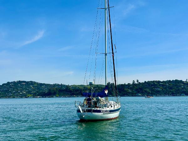 Sailboat Valiant 39 (1996) on calm water with scenic hills in the background.