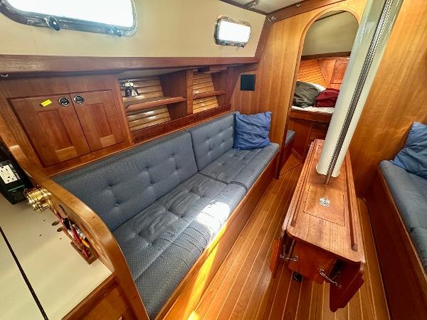 Interior of a 1996 Valiant 39 sailboat with wooden furnishings and blue cushions.