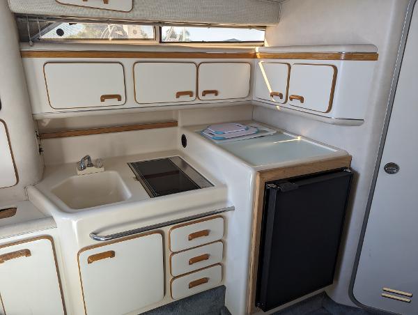 1992 Sea Ray 330 Express Cruiser kitchen with sink, stove, and compact fridge.