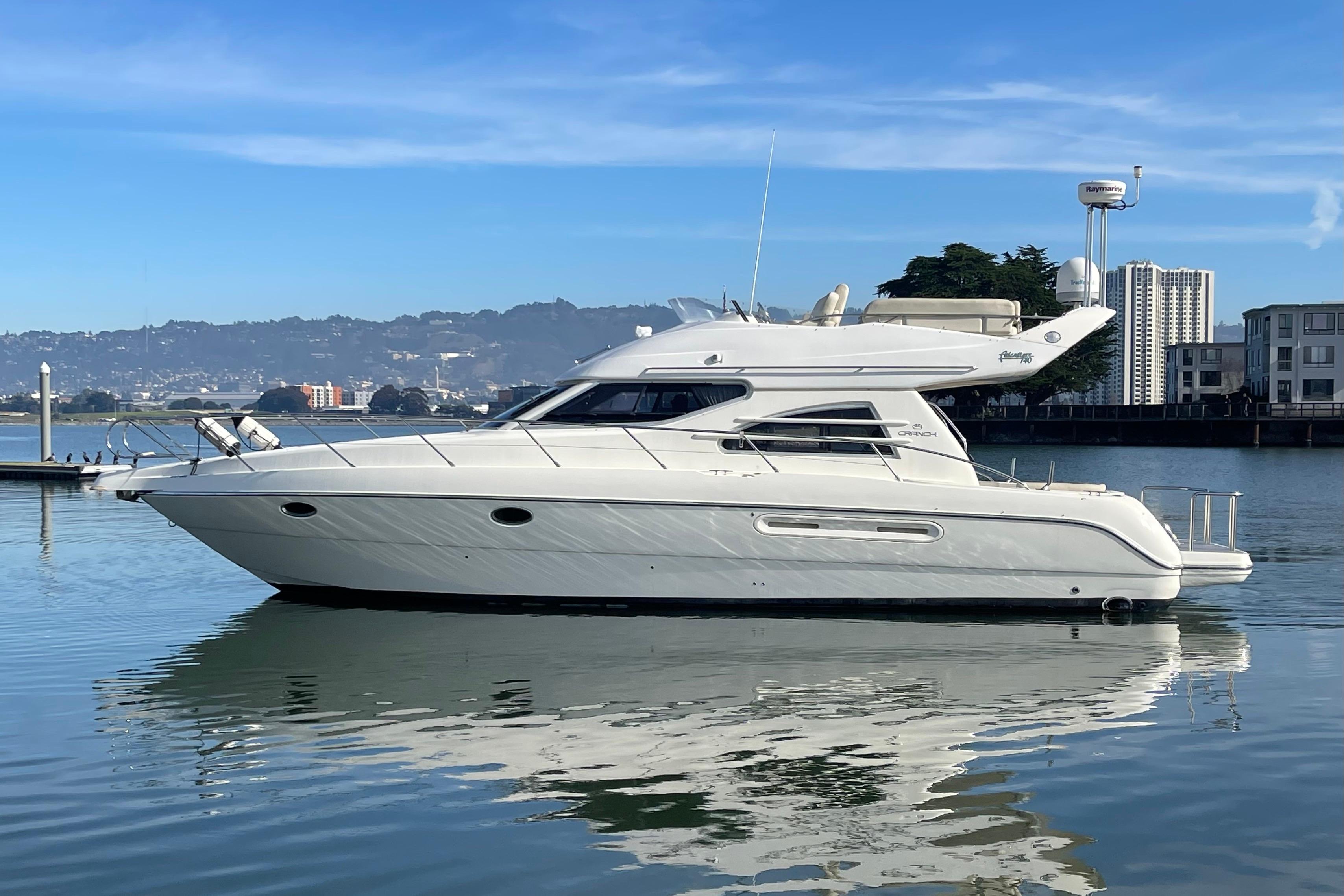 2003 Cranchi Atlantique 40 yacht on calm water with cityscape background.