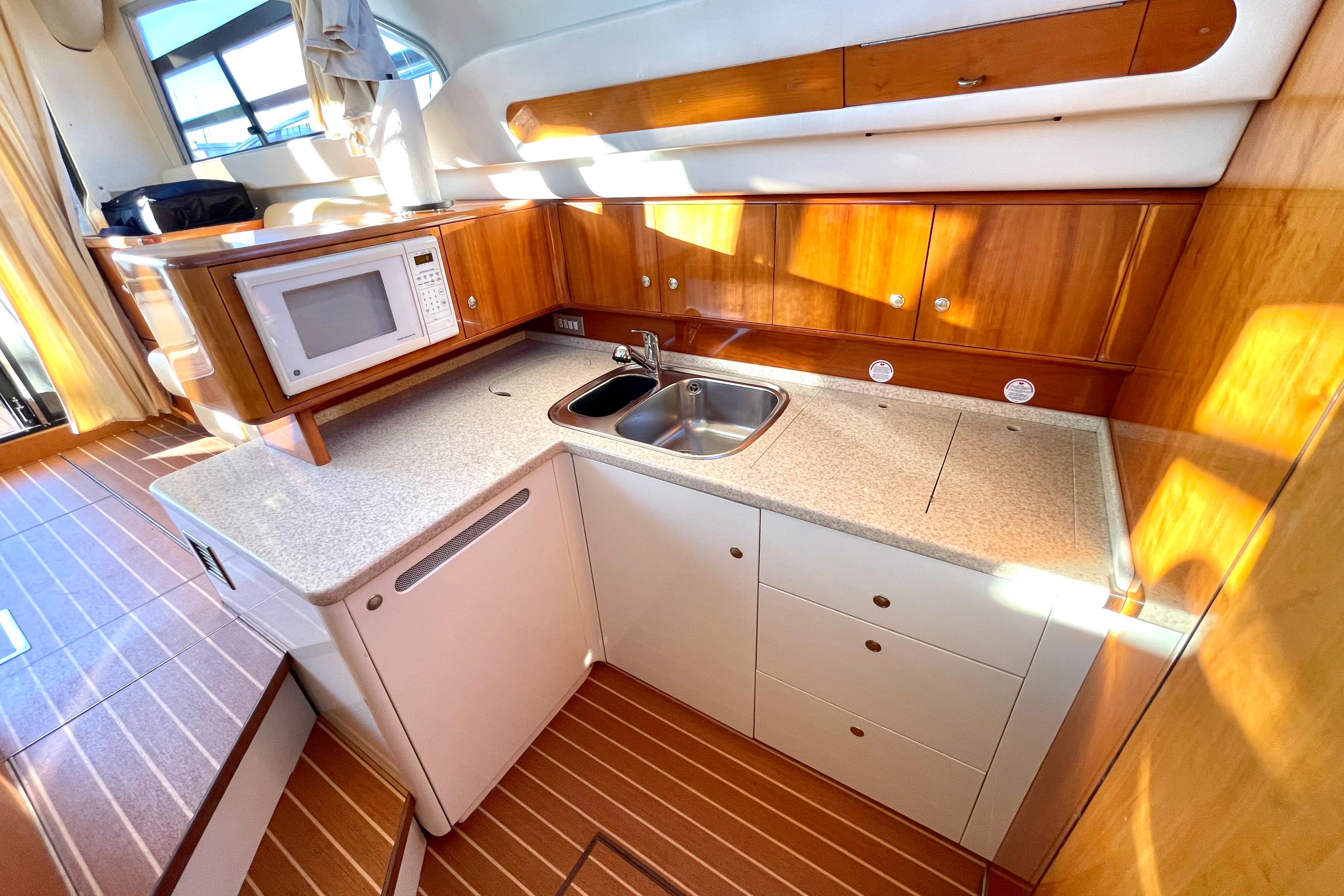 Luxurious kitchen interior of 2003 Cranchi Atlantique 40 yacht with wood cabinetry and modern appliances.