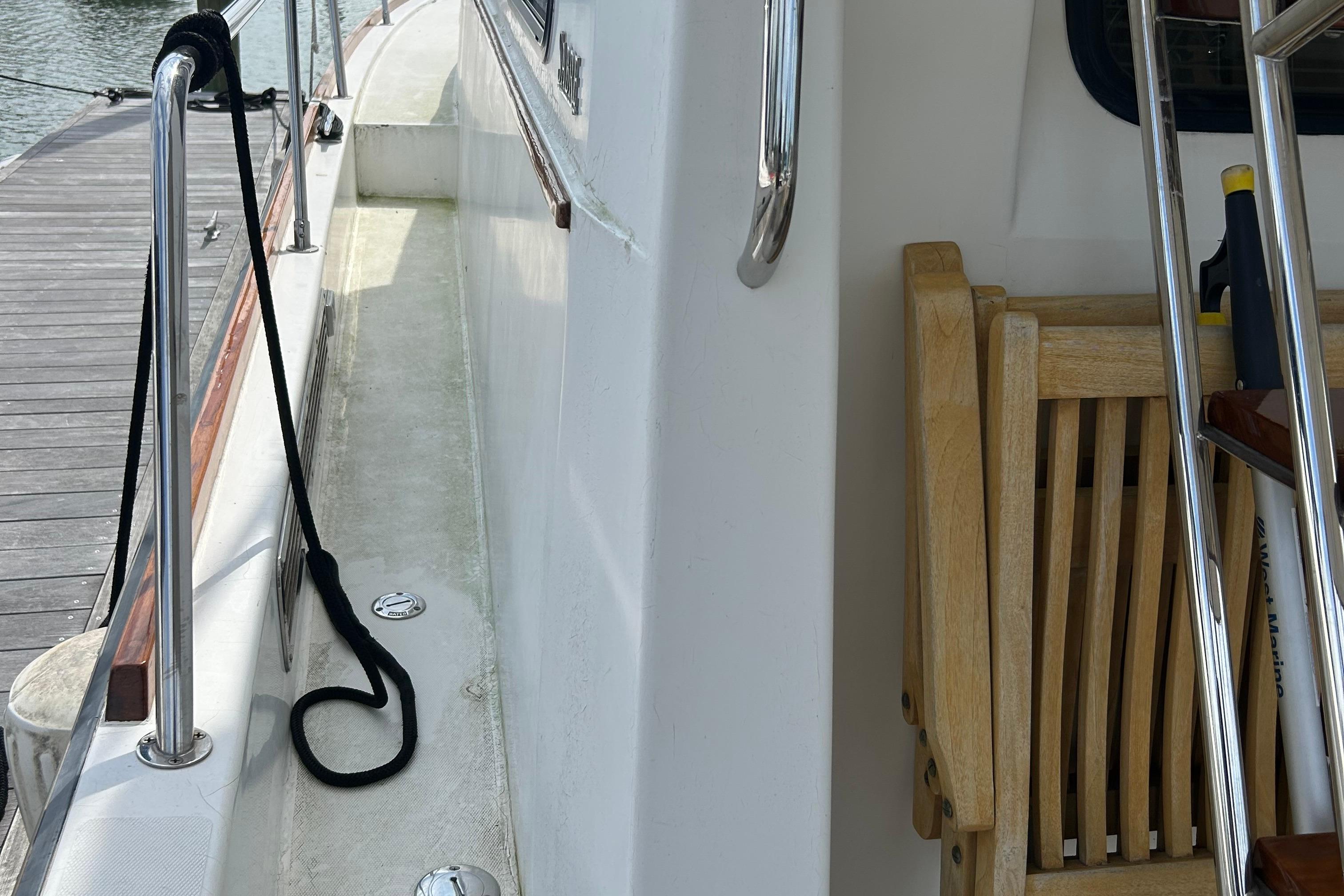 Side deck of 2004 Sabre 36 FB yacht with wooden chair and railing.