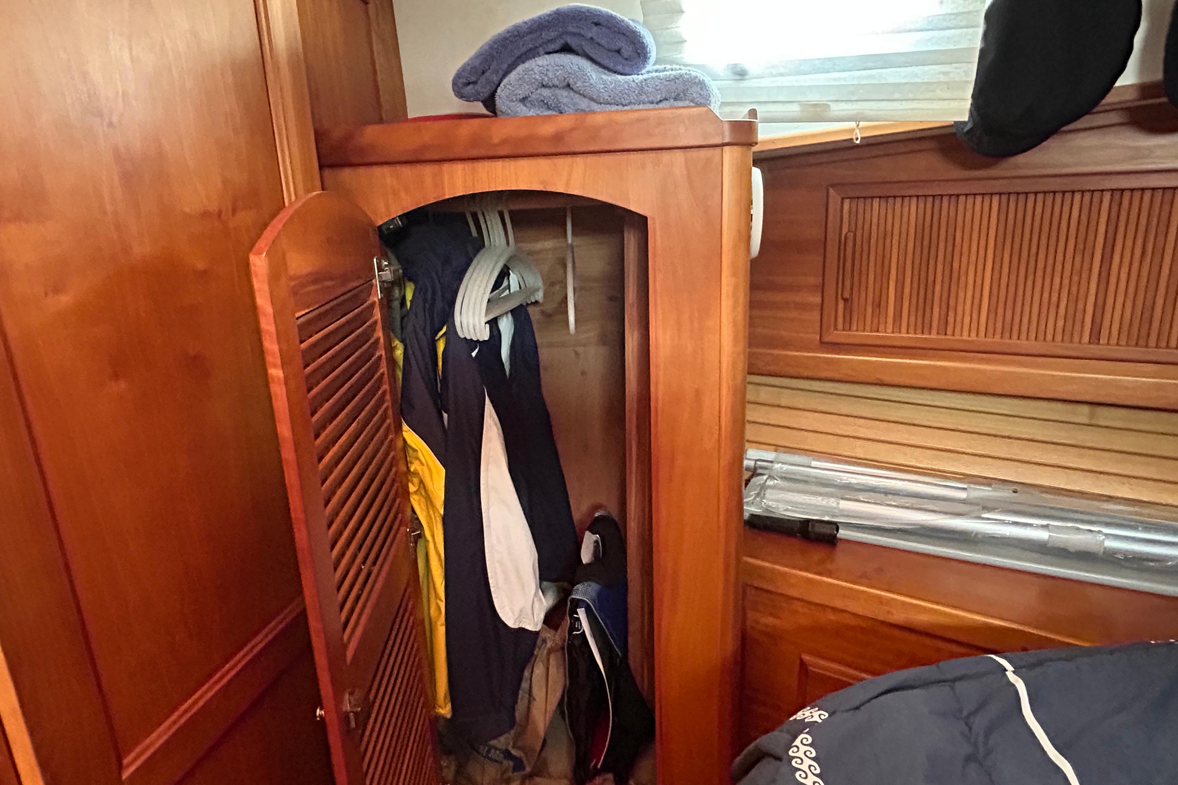 Wooden closet with hanging clothes inside a 2004 Sabre 36 FB boat interior.
