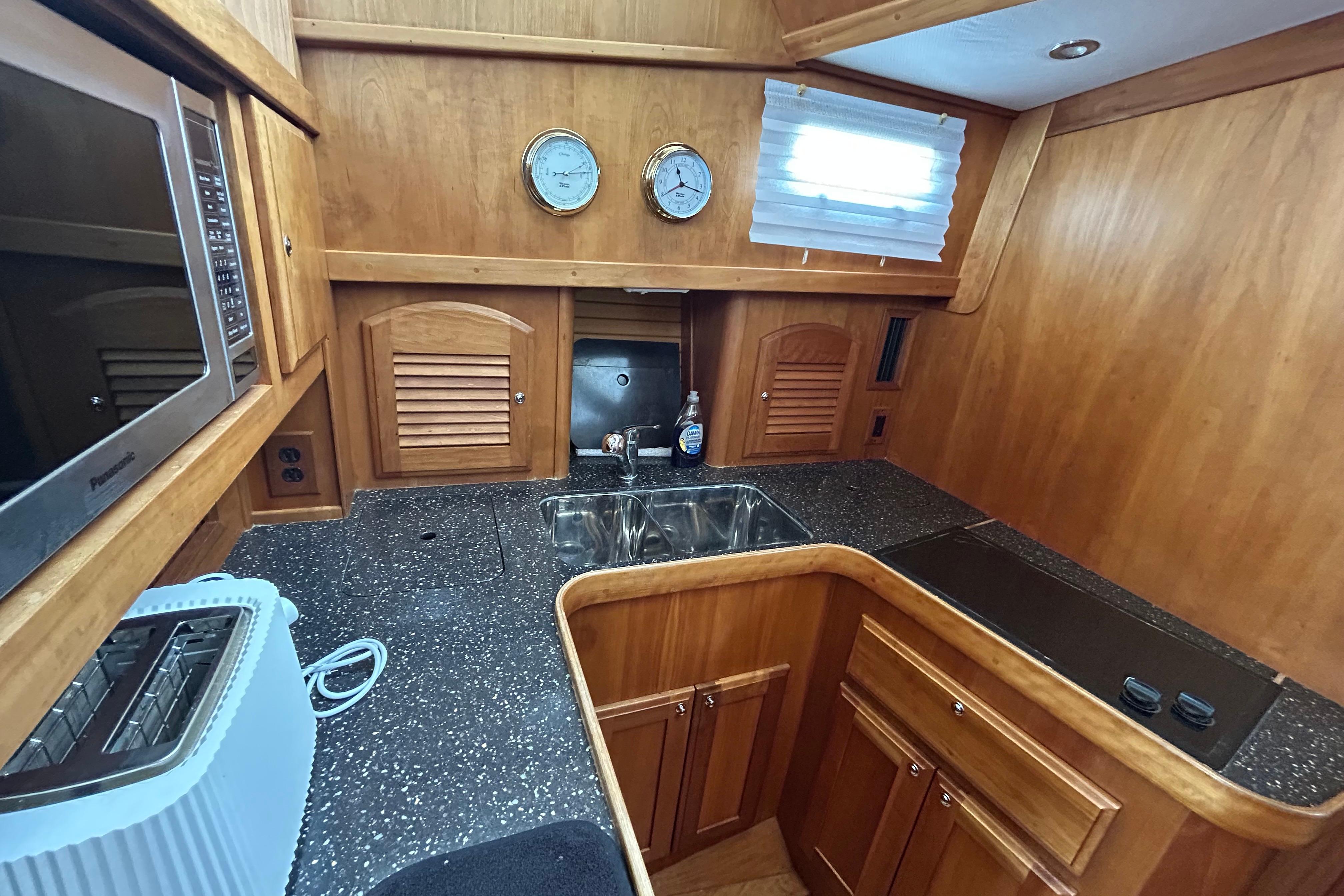2004 Sabre 36 FB yacht kitchen with wooden cabinetry, sink, and appliances.