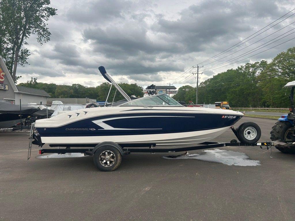 2017 Chaparral 21 H2O Sport boat on trailer, parked outdoors under cloudy sky.