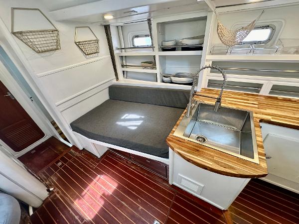 Cozy interior of 1983 Tayana 55 yacht with wooden countertops and seating area.