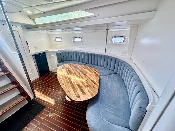 Luxurious 1983 Tayana 55 yacht interior with curved seating and wooden table.