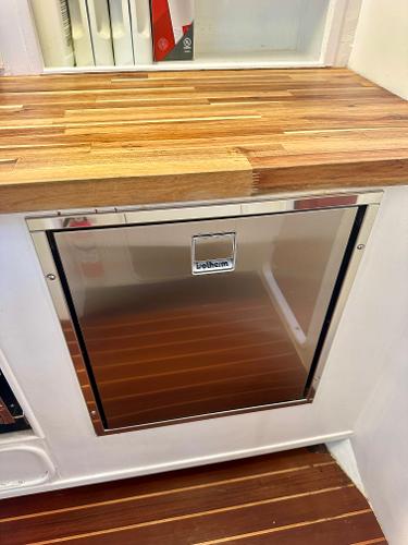 Stainless steel fridge on Tayana 55 yacht, 1983 model, with wooden countertop and flooring.