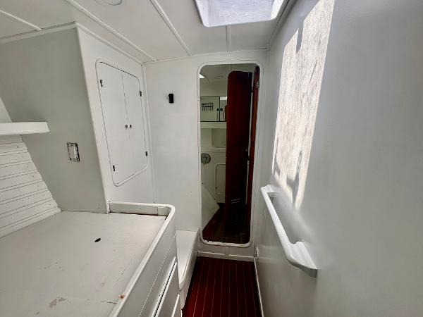 Interior of 1983 Tayana 55 yacht, featuring white walls, wooden floor, and natural light.