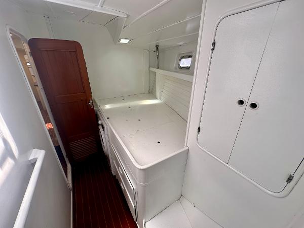 1983 Tayana 55 yacht interior with white cabinetry and wooden flooring.
