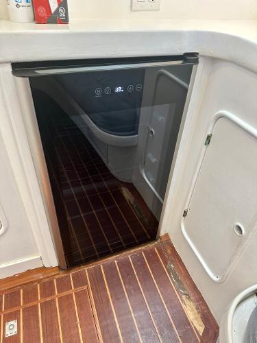 Compact refrigerator in 1983 Tayana 55 yacht interior with wooden flooring.
