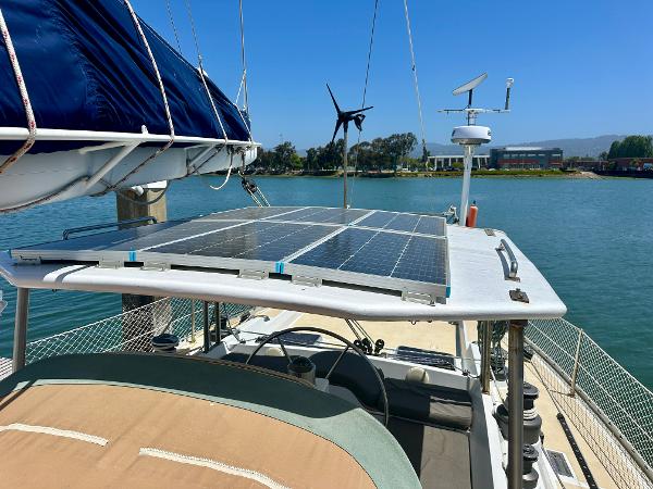 Sailboat with solar panels on deck, Tayana 55, 1983 model, docked by a scenic waterfront.