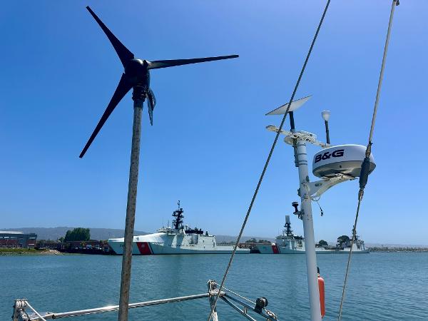 Sailboat with wind turbine and radar, Tayana 55, 1983, near coast guard ships.
