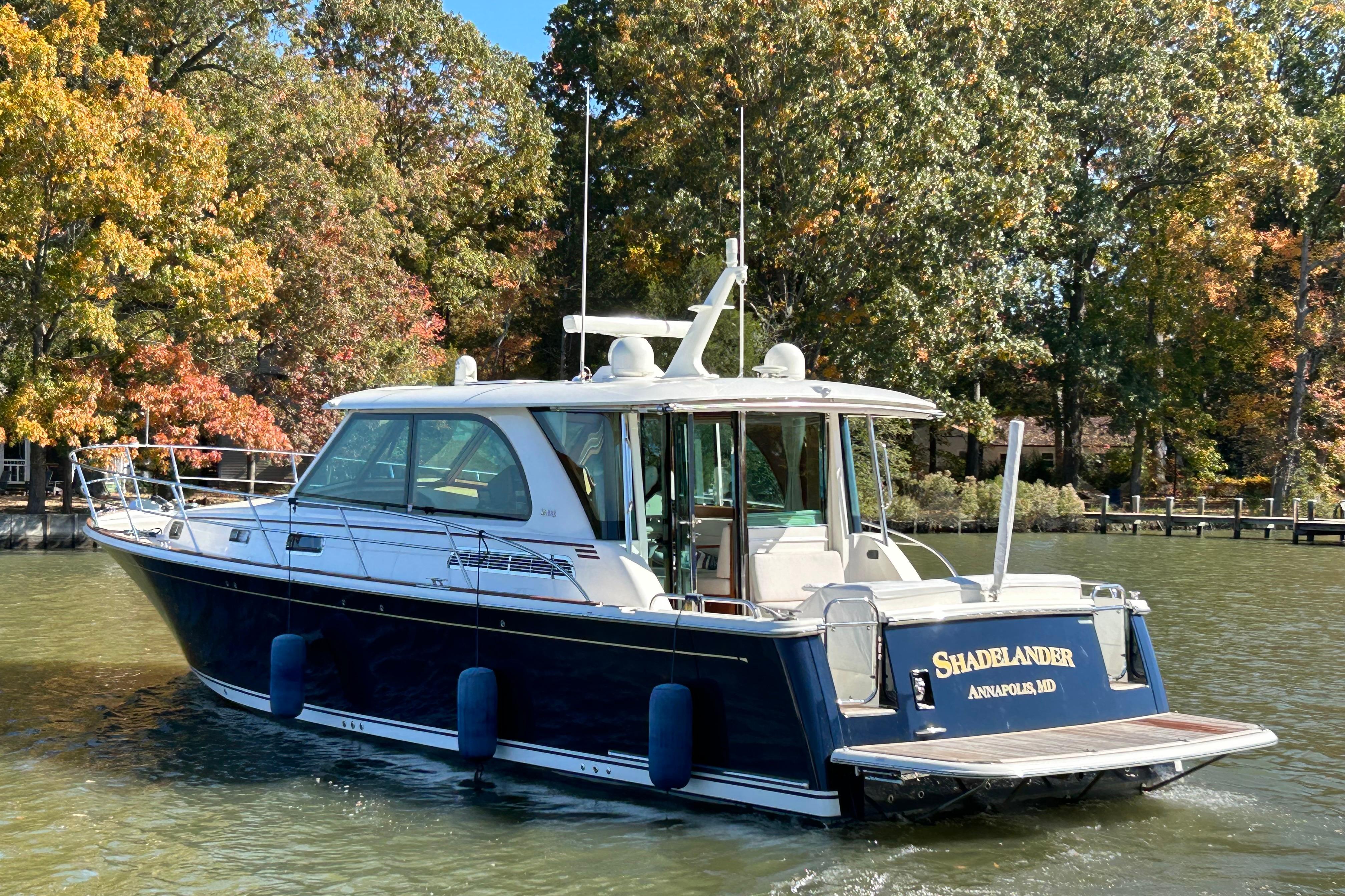 2022 Sabre 45 Salon Express yacht cruising on a scenic lake with autumn foliage.